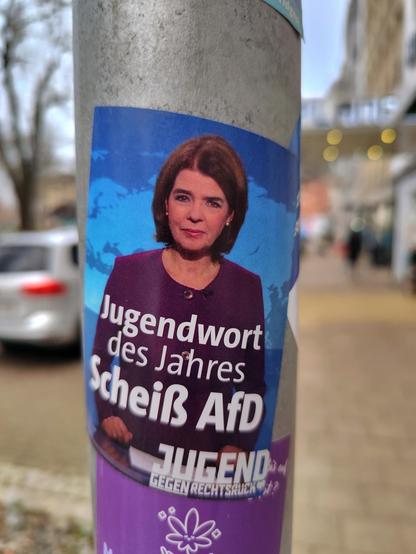 Sticker an einer Laterne mit einer Tagesschaufrau und dem Aufdruck Jugendwort des Jahres Scheiß AFD. Jugend gegen Rechtsruck.