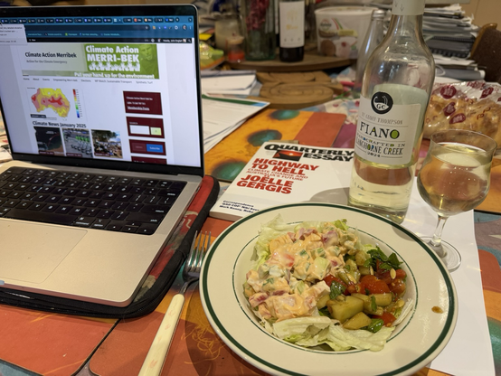 Salads and wine for Dad’s dinner next to a laptop showing Climate Action Merribek front page.