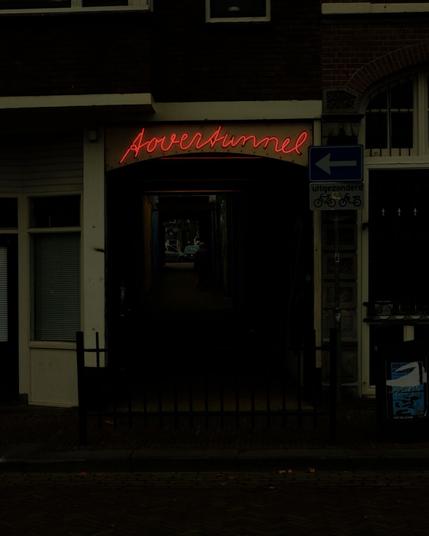 Dark passage with a glowing red neon sign reading ‘Tovertunnel,’ creating a moody, urban atmosphere. Captured with a Fuji X-T1.