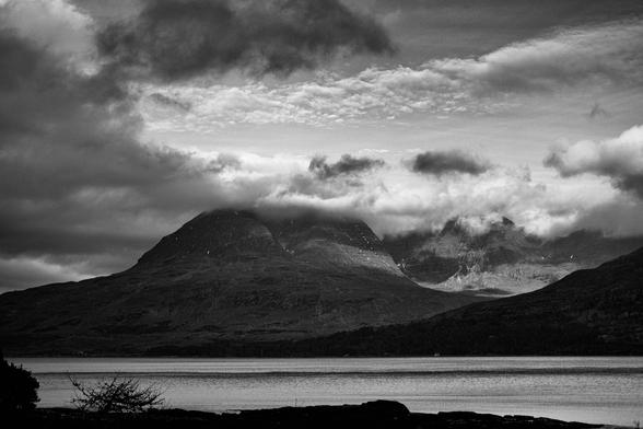 A black and white photo of sunlit clouds moving across Beinn Alligin above a gloomy Upper Loch Torridon. Torridon, Wester Ross, Scottish Highlands.

Photo by and copyright of Lynn Henni.