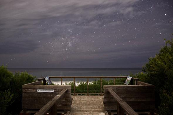 The Milky Way slightly visible over an observation deck that looks out over the beach