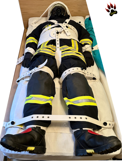person in (complete) firefighter gear bound to a bed in Segufix restraint system, full view