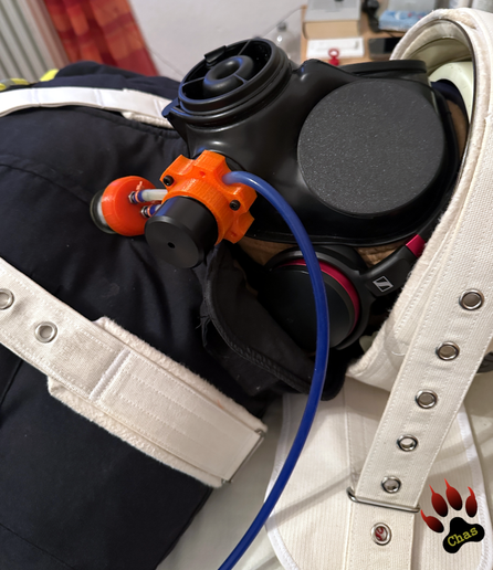 closeup (sideview) to the head of a person wearing firefighting gear, S10 gasmask with blackout caps and a Poppers Pump and helmet, tied to the bed with Segufix restraint system