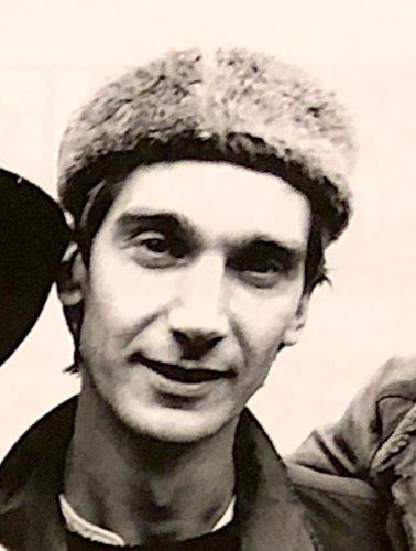 A black and white photo of a smiling man (Mick Hobbs) wearing a furry hunter hat.