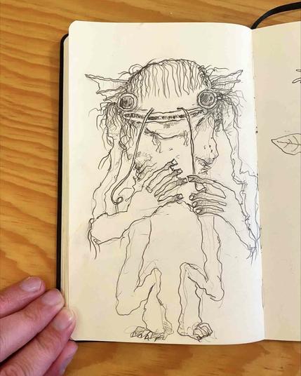 Fotografía de un cuaderno con un dibujo a lápiz de una criatura mitad humano mitad bagre