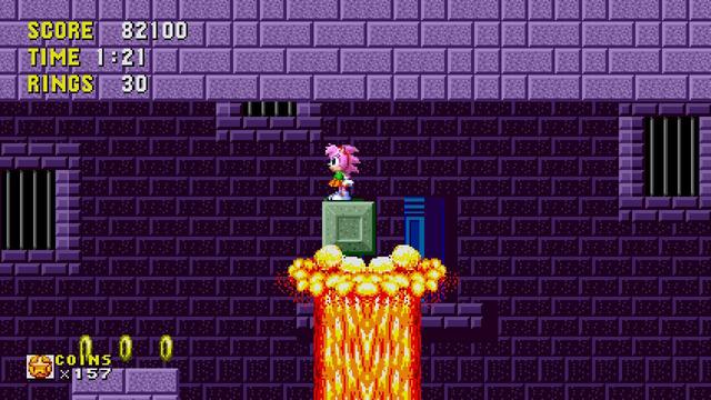 A screenshot of the "original" Sonic the Hedgehog in Sonic Origins on the Switch.

I'm playing as Amy Rose and taking a ride on a block on top of a magma spout in the Marble Zone. Aside from the yellow-orange-red lava and the green push-block, it's all very purple: the platforms and ceiling are purple bricks, and the background is darker purple bricks with barred windows.