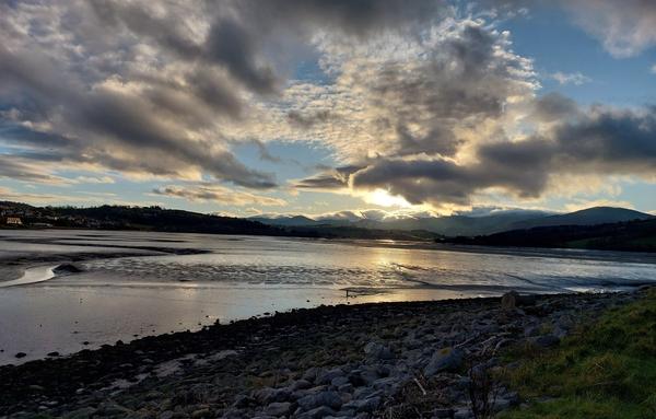 A shot over Colwyn Bay with the tide out showing the wet sand reflecting the low winter sun. The clouds behind the mountains look like mountains themselves.
