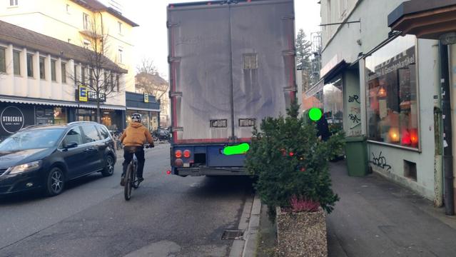 Die Situation aus der Nähe. Ein Blumentrog soll wohl die Nutzung des Gehweges durch KFZ verhindern. Ein anderer, jugendlicher, Radfahrer wieder fast in Fahrbahnbitte. Jetzt gefährlich nahe dem Gegenverkehr.