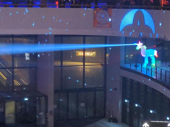 A glowing unicorn standing on a balkony inside a larger hall, with a light beam coming from its head. its an illusion, there is actually a spotlight mounted above the unicorn, but the perspective does a lot.