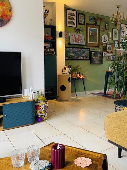 A calico cat named Pixel sitting on a scratching post in a colorful living room.