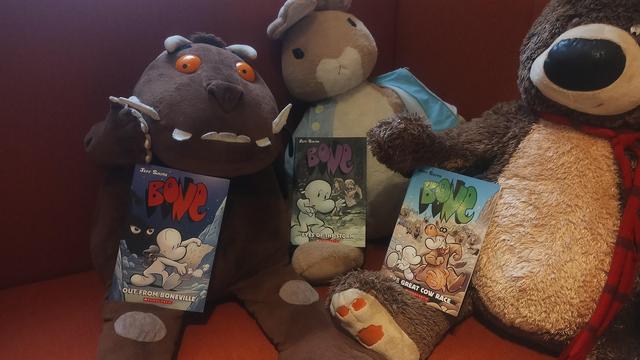 Cuddly Gruffalo, Peter Rabbit and Hugless Douglas plushes in the Edinburgh Bookshop's children's room, all holding a copy of different volumes of Jeff Smith's all-ages graphic novels, Bone