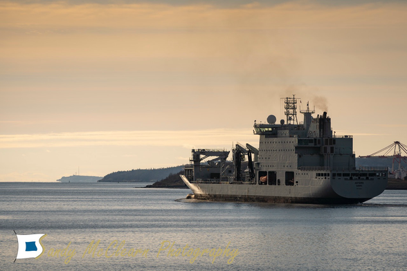 Ship leaving port at dawn.