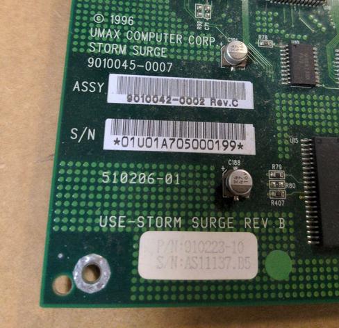 A closeup of the corner of the motherboard with the labels. Screenprinted in white: © 1996 UMAX COMPUTER CORP. STORM SURGE 9010045-0007 above two barcodes. Below the barcodes is screenprinted 510206-01 USE-STORM SURGE REV B
