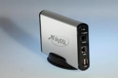 Low-resolution photo of a "skyDSL BOX", a gray brushed aluminium flat case ona vertical stand with the skyDSL logo on the side.

It is seen from the front at a 45° angle, showing the plastic endcaps and Analog, ISDN & USB plugs at front!