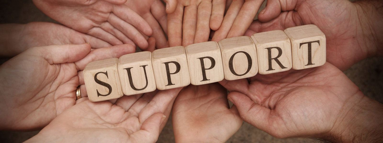 An image with several human hands holding several wooden blocks that spell out the word SUPPORT.