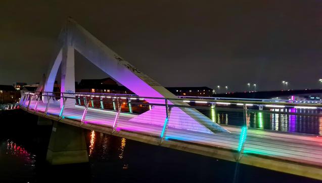 A pedestrian bridge, lit up at night, across the Clyde in Glasgow.