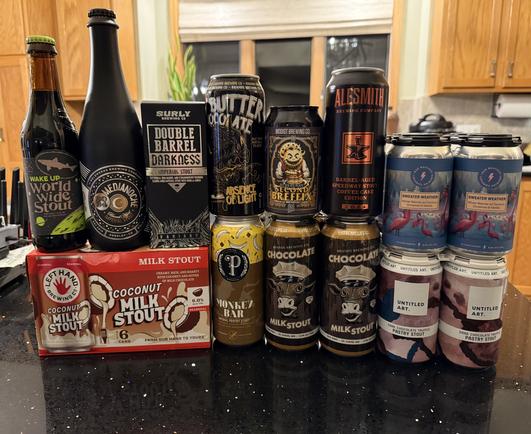 An array of beer bottles and cans. World Wide Stout, Medianoche, Lefthand Coconut Milk Stout, Double Barrel Darkness, Breffix, Monkey Bar, AleSmith, Chocolate Milk Stout, Chocolate truffle, Sweater Weather