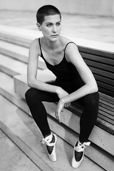 Ballerina sits on a bench in Hamburg's HafenCity in a pointed-foot position