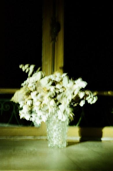 Bouquet de fleurs blanches devant une ancienne fenêtre la nuit, éclairé avec une lampe torche.