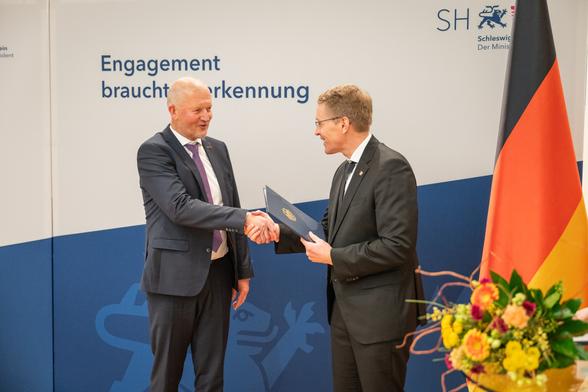Ministerpräsident Daniel Günter überreicht Prof. Dr. Olaf Köller die Ehrung.