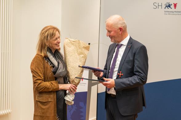 Bildungsministerin Karin Prien überreicht Prof. Dr. Olaf Köller Blumen und ein Geschenk.