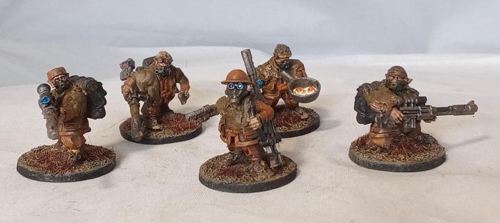A team of 5 diminutive Ratling Snipers. They wear brown rags over prison orange uniforms, wield sniper rifles, and wear a variety of gasmasks. One chap at the back has a frying pan.
