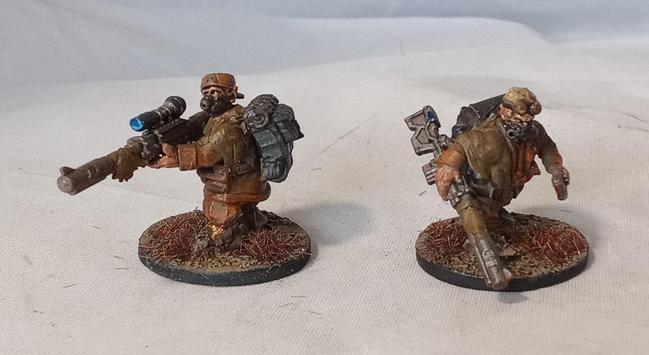 Two Ratling Snipers. They wear brown rags over prison orange uniforms, wield sniper rifles, and wear a variety of gasmasks. The one on the left is aiming, the one on the right is striding forwards.