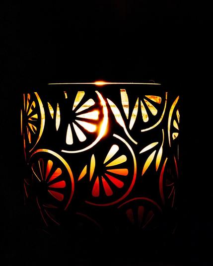 A close up a candle light surrounded by a candle shade that has cut out of citrus slices