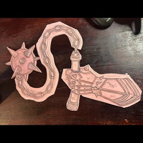 Pink printmaking blocks that have been cut into a gauntlet holding a chain mace.