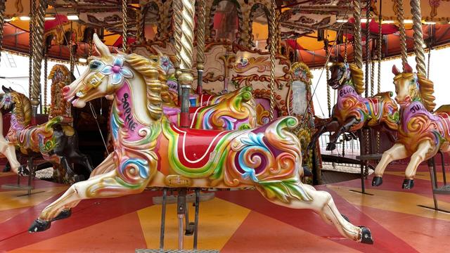 A golden horse sprints on a fairground carousel. Her name, Sophie, is printed on her neck. She has colourful swirls on her body and a red saddle