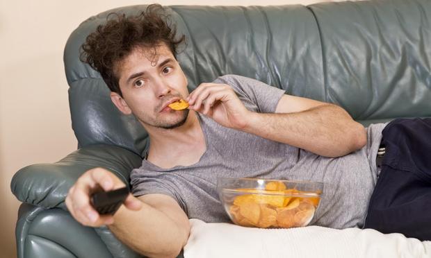 Un hombre comiendo chucherías mientras ve el fútbol. (Getty Images)