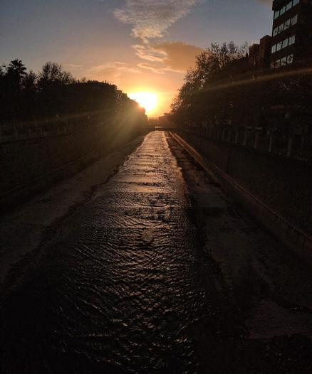 Vista del río Genil desde el puente de San Antón al atardecer. Los últimos rayos del sol se reflejan en el agua y en las ventanas de los edificios que hay a la orilla del río.