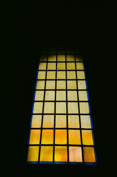 A contrasted shoot of a stained glass window in the dark from the inside of a church