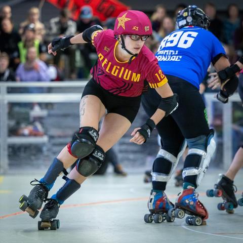 A color photo of a Roller Derby jamming person from Team Belgium Roller Derby rounding behind a blocker from Team Italy Roller Derby