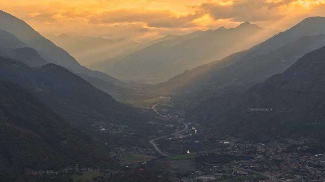 Una foto della valle d'Aosta, vista dall'alto. Si vede la strada che divide in due le catene montuose che circondano la valle.