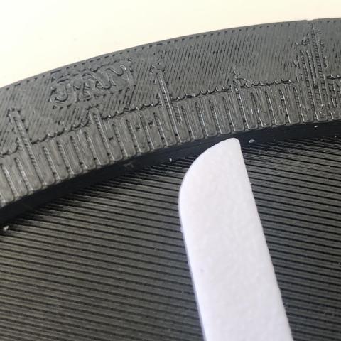 Physical moon phase calculator, made out of 3d printed parts and gears. The device is black and round, with a white calendar pointer on one side and a moveable moon phase indicator on the other.