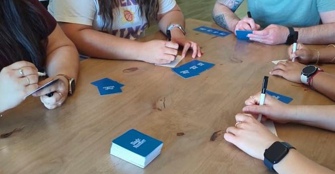 People playing the Magic Number card game at a table - just their hands and the cards, all face down
