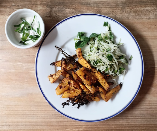 Auf einem Teller die Steckrüben-Stücke (fast wie Pommes) und Thymianzweige, etwas von dem Salat, ein Pfefferminzzweig.
Neben dem Teller eine Schale mit Joghurt + Frühlingszwiebeln