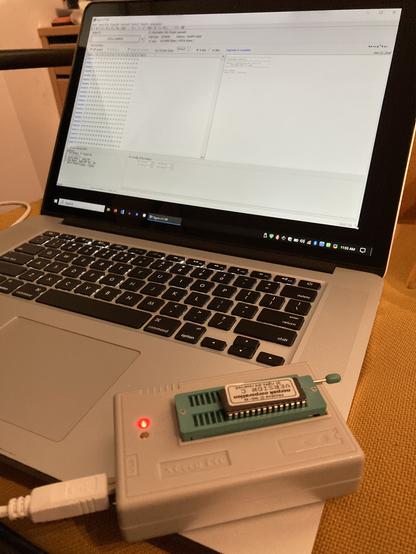 An EEPROM programmer with a chip inserted inside. XGpro runs only in windows, showing in the background on my very unhappy mac pro.