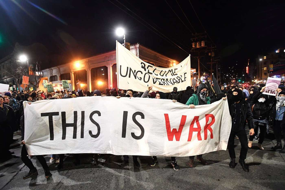 Demonstrators mobilize in Berkeley, California at the beginning of Donald Trump’s first term. They carry a banner reading "this is war" and another reading "become ungovernable."