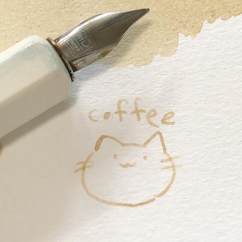 コーヒーで作ったインクの試し書き。猫のイラストと「coffee」の文字。