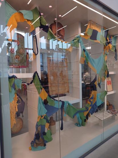 a display at The Box, Plymouth showing some objects from the museum. Craft Collective (I call it knitting group!) made pieces that are different shapes and sizes and joined together. This big piece is hung around the objects.