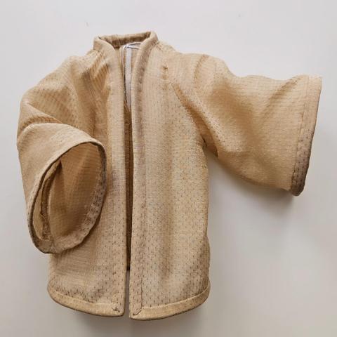 Picture of an offwhite shirt shaped like a kimono with a light fabric.