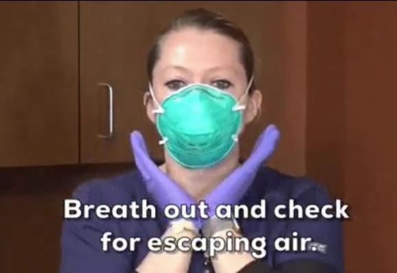 Eine Frau mit grüner FFP-Maske.
Darunter steht:
Breath out and check for escaping air.