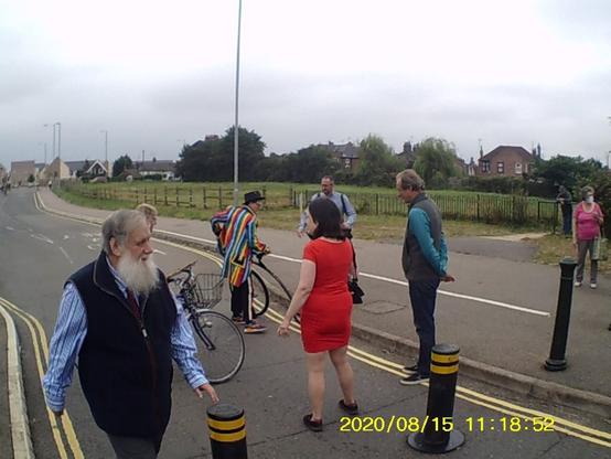 People with bikes standing around on the entrance to a bus/cycleway, August 2020
