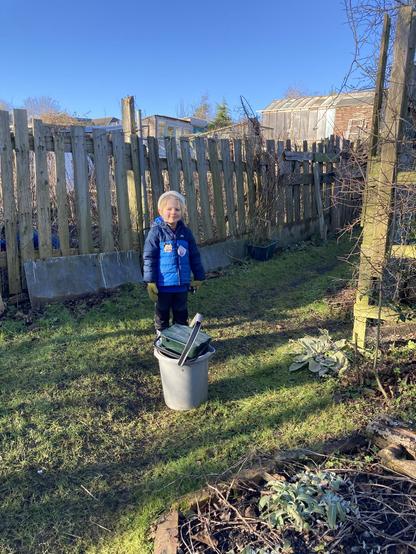 A boy and some buckets on grass in some allotments on a sunny winter day