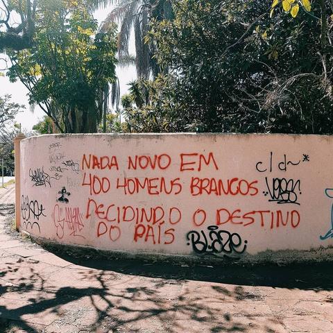 Alt text: Graffiti on a wall with a political statement in Portuguese.