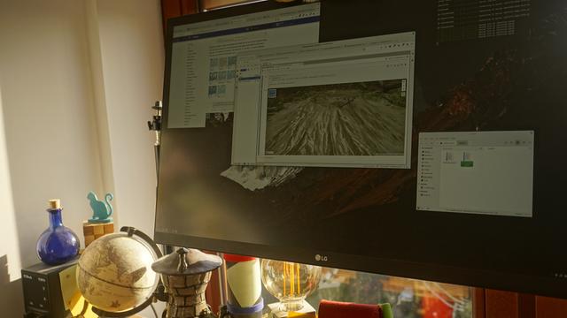 A picture of my monitor on a sunny day. On the screen there are a couple of windows open, notably a web browser with a JupyterLab open and a view of a 3d rendered map.