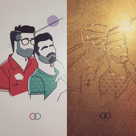 Una impresión de arte vectorial en papel junto a su correspondiente versión grabada en una placa de bronce. 
La imagen representa a un hombre con gafas abrazando desde detrás a otro hombre Ambos llevan barba. En el fondo, se ve la estela de un avión por el cielo.