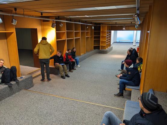 Blick auf den ehemaligen Schuhladen im früheren Sport Sohn in Neu-Ulm. Menschen sitzen auf den Bänken rundherum, alles ist noch leer